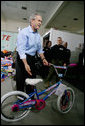 President George W. Bush helps guide a donated bicycle to a toy distribition vehicle, Monday, Dec. 19, 2005, at the "Toys for Tots" collection center at the Naval District Washington Anacostia Annex in Washington, D.C. White House photo by Kimberlee Hewitt