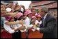 President George W. Bush is greeted by the Afghan girls soccer team after delivering remarks to the athletes at the International Children's Games and Cultural Festival in Cleveland, Ohio, July 30, 2004. White House photo by Paul Morse.