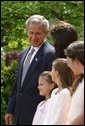 President George W. Bush looks toward Lacy Lyons, center, before signing the S. 151, PROTECT Act of 2003, in the Rose Garden Wednesday, April 30, 2003. Abducted by their father, Lacy, 10, and her sister Nyoka, 8, left, were found after an AMBER alert was activated throughout the state of Florida. White House photo by Paul Morse