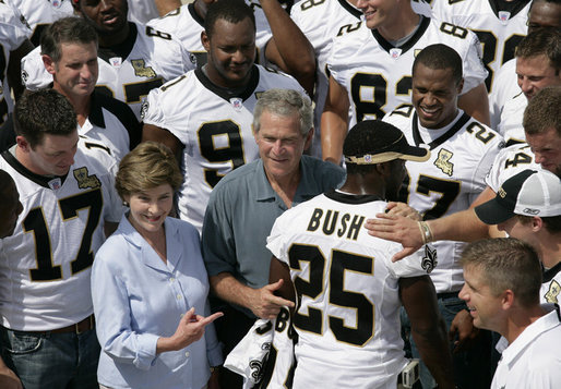 President George W. Bush and Laura Bush are surrounded by members of the New Orleans Saints football team Tuesday, Aug. 29, 2006, as they point out the name of Saints star rookie running back Reggie Bush, when the team met President Bush at the New Orleans Airport to pose for a team photo. White House photo by Eric Draper