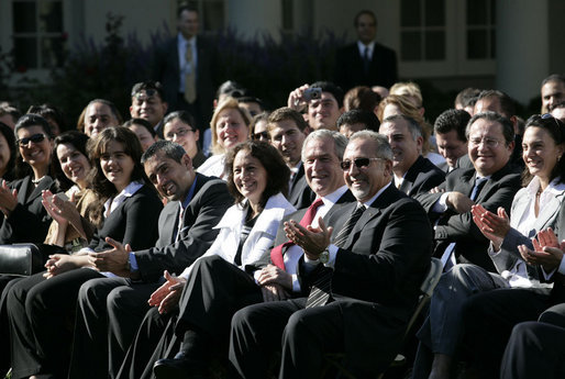 President George W. Bush joins the Rose Garden audience during a celebration Wednesday, Oct. 10, 2007, of Hispanic Heritage Month at the White House. Sitting with the President is Yamile Llanes Labrada, the wife of a political prisoner in Cuba, and Emilio Estefan. White House photo by Eric Draper