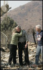 President George W. Bush hugs Kendra Jeffcoat as her husband Jay stands by in the midst of the charred rubble of their Rancho Bernardo, California home. The President met the couple during his visit Thursday, Oct. 25, 2007, to the Southern California areas ravaged by recent wildfires. White House photo by Eric Draper