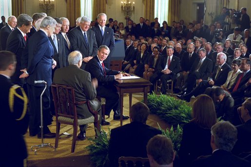 President George W. Bush looks toward Senator Jesse Helms after signing the H.J. Resolution 114 authorizing the use of force against Iraq in the East Room Wednesday, Oct. 16. "I thank the Congress for a thorough debate and an overwhelming statement of support. The broad resolve of our government is now clear to all, clear to everyone to see: We will defend our nation, and lead others in defending the peace," said President Bush. White House photo by Paul Morse.