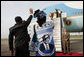 Tanzanian President Jakaya Kikwete and first lady Salma Kikwete, wearing a blouse imprinted with a likeness of President George W. Bush, wave farewell to President Bush and Mrs. Laura Bush Tuesday, Feb. 19, 2008 at Julius Nyerere International Airport in Dar es Salaam, Tanzania. White House photo by Eric Draper