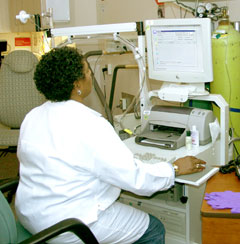 Technician sitting at computer viewing pulmonary test results.