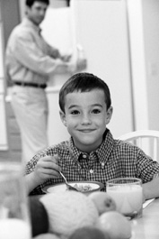 Photo of young boy smiling eating a bowl of cereal.