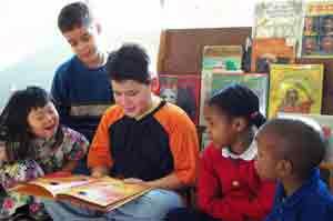 a grade school student reading from a book to other classmates in their classroom