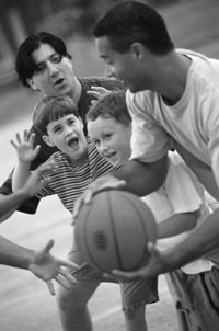 Photo of two men and two boys playing basketball.