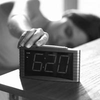 Photo of woman hitting the snooze button.
