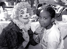 Photo of a clown painting a child's face