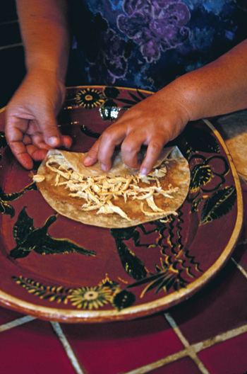 woman cooking a tortilla on pottery