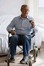 Image of man in wheelchair looking at a pill bottle