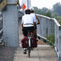 Two people riding bikes over a bridge