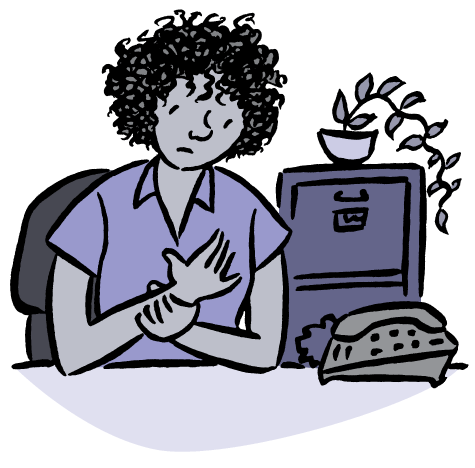 Woman at desk holding wrist