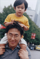 A photo of father carrying a kid over his shoulder