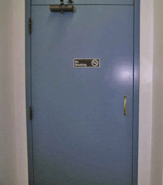 Inaccessible toilet room door at end of long narrow hallway