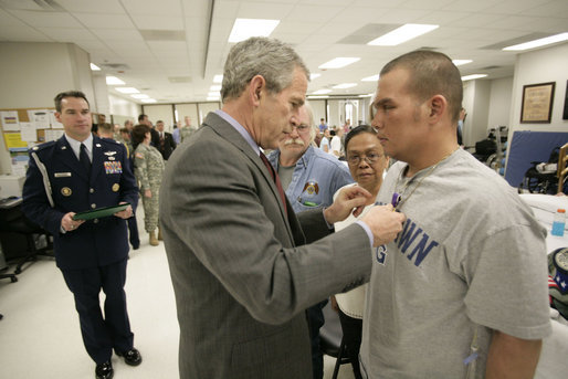 President George W. Bush presents the Purple Heart to U.S. Army Private First Class Casimir Domingo Werda of Novi, Mich., during a visit Friday, March 30, 2007, to the Walter Reed Army Medical Center in Washington, D.C. Werda is recovering from injuries sustained in Operation Iraqi Freedom. Werda's parents Floserfina Demano Werda and Gregory Lee Werda are seen background. White House photo by Eric Draper
