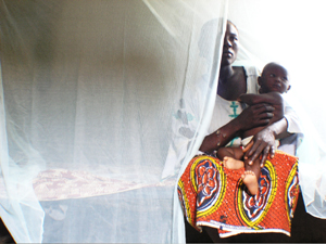 A Nigerian woman and her baby show their insecticide-treated bed net.