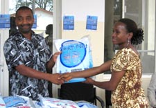 Ali Khamis Abbas presents a long-lasting insecticide-treated net to Consolata John.