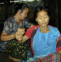 A woman who appears ill being helped by a health worker