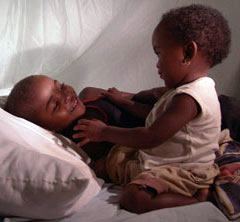 Photo of two children underneath a mosquito net.