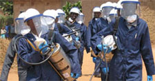 Photo of IRS spray operators in Rwanda wearing full protective gear and carrying spraying equipment.