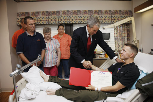 President George W. Bush shakes hands with U.S. Marine Corps Pfc. Charles Cozart of Arizona City, Ariz., Thursday, July 3, 2008, after awarding Cozart with a Purple Heart medal and citation at the National Naval Medical Center in Bethesda, Md. Joining the ceremony, background, are his father and mother, Kevin and Sharon Cozart, and his grandparents, Arthur and Betty Cozart. White House photo by Eric Draper