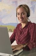 A young woman using a laptop with a headset on