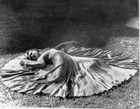 Betty, a Calla Travis Dance School instructor, takes a sensuous pose in a benefit performance of "Fantasy." She iswearing a costume she designed consisting of a grey satin skirt and leotard with magenta sash and gloves. Grand Rapids, Michigan. 1942. 