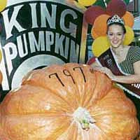 Photo: young woman in a tiara posing with huge pumpkin.  Sign  with "King Pumpkin" in background.