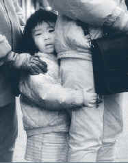 Photo of young child standing between two adults