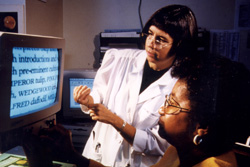 A woman reading enlarged text off a computer screen with a doctor standing beside her