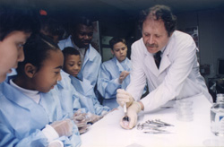 A doctor addressing multiple students dressed in lab coats