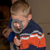Young boy looking through magnifying lens.
