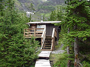 Black Bear Cabin sits in a grove of mountain hemlock backed by a steep alpine slope and rock face.