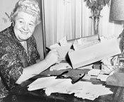 A woman at a desk piled high with letters