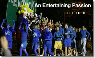 Painted blue, large group of UK students parade with a Kentucky flag with words An Entertaining Passion + read more