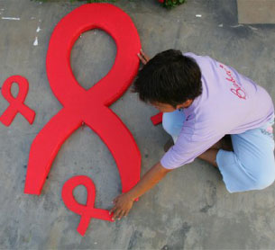 An HIV-positive mother prepares an AIDS symbol