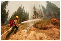 Photo of firefighter spraying water onto Montana wildfire