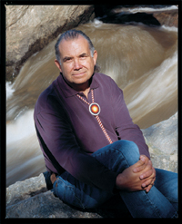 Ted Mala seated on boulders by a rushing river