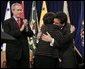 As President Bush leads the applause, Attorney General Alberto Gonzales embraces his mother, Maria, after he was ceremoniously sworn into office Monday, Feb. 14, 2005, at the Justice Department. White House photo by Paul Morse.