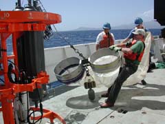 Deck crew and scientists pulling up bongo nets used to sample sea life during the cruise around the volcano.