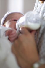 Photograph of a mother feeding a baby a bottle