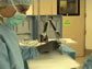 Screen capture from video showing surgeon and robot in an operating room