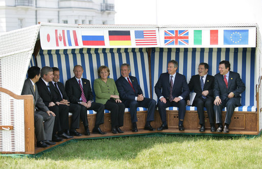 Leaders of the G8 sit on a canopied bench after meeting with Junior G8 Student Leaders Thursday, June 7, 2007, in Heiligendamm, Germany. From left, and under their respective country flags, are: Prime Minister Shinzo Abe of Japan; Prime Minister Stephen Harper of Canada; President Nicolas Sarkozy of France; Chancellor Angela Merkel of Germany, President George W. Bush of the United States; Prime Minister Tony Blair of the United Kingdom; Prime Minister Romano Prodi of Italy, and Jose Manuel Barroso, President of the European Commission. White House photo by Eric Draper