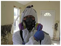 Scientist fully enclosed in protective clothing in a once flooded residence.