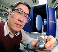 Materials engineer Duck Young Chung examines a sample of superconducting crystals before characterizing them in a X-ray diffractometer