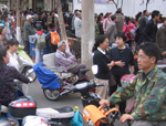 Photo shows e-bikes and people on a congested street in China.