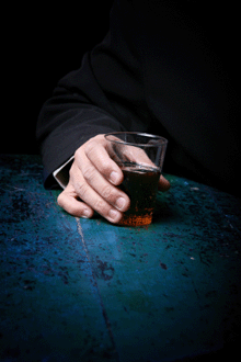 Photo of a hand holding a glass with an alcoholic drink.