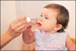 Foto: una niña pequeña toma una medicina de mano de un adulto.